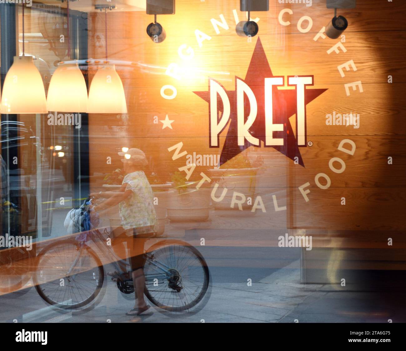 New York, USA - 26. Mai 2018: Schnelles, ungezwungenes Restaurant Pret A Manger Logo mit einem Spiegelbild der Straße von New York. Stockfoto