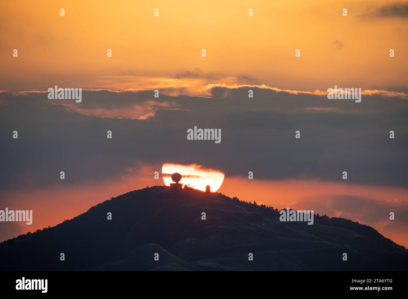 Spektakuläre Nahaufnahme des Sonnenuntergangs. Orangefarbener, flammender Himmel. Im Vordergrund befindet sich die Wufenshan Wetterradar-Station. Ruifang, Taiwan. Stockfoto