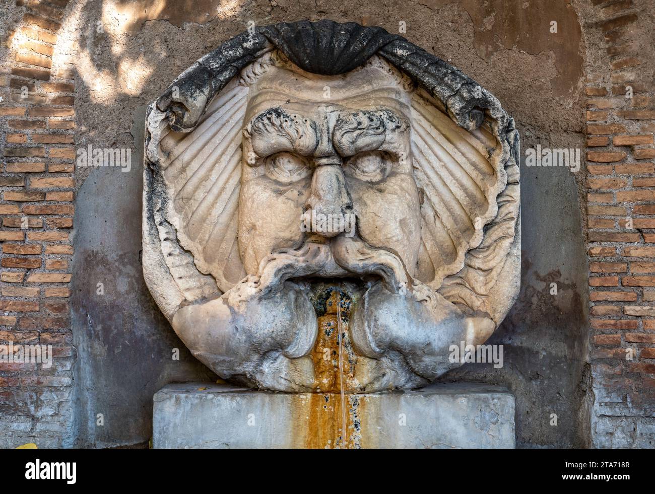 Nahaufnahme eines antiken römischen Brunnens aus Marmor, der das Gesicht eines wütenden und haarigen Gottes darstellt Stockfoto