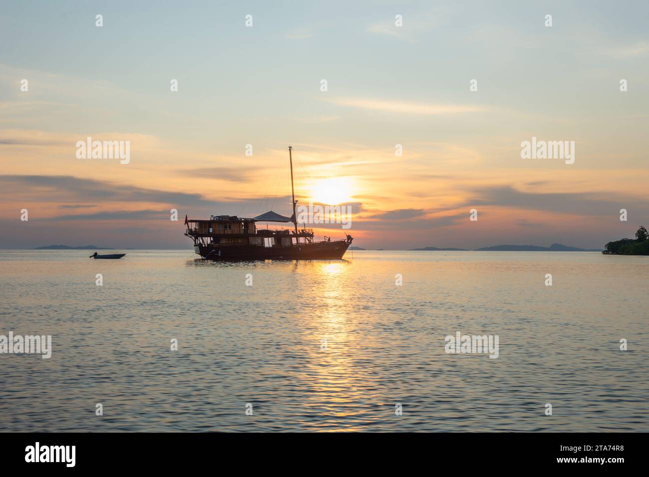 Silhouette eines Bootes, das bei Sonnenuntergang im Ozean verankert ist, Wayag, Raja Ampat, West Papua, Indonesien Stockfoto