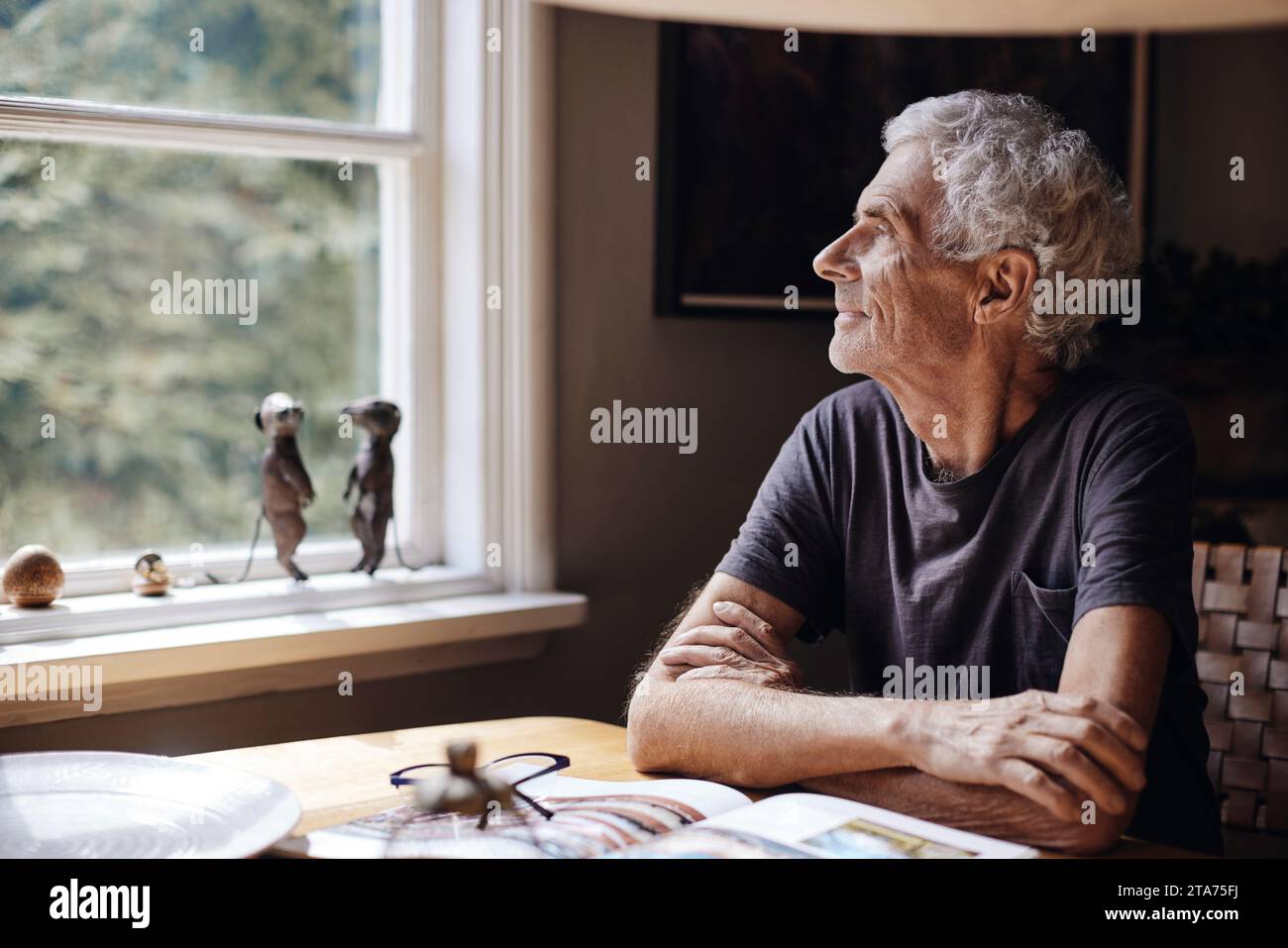 Ein besinnlicher Seniorenmann, der zu Hause durch das Fenster schaut Stockfoto