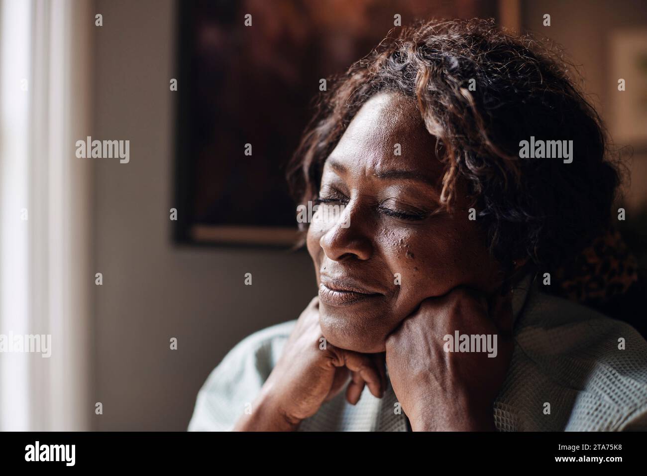 Reife Frau mit geschlossenen Augen, die zu Hause träumt Stockfoto