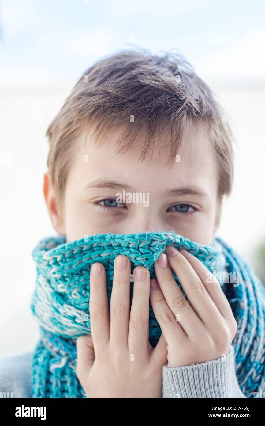 Nahporträt eines Jungen, der einen gestrickten Schal über dem Mund hält, Georgia Stockfoto