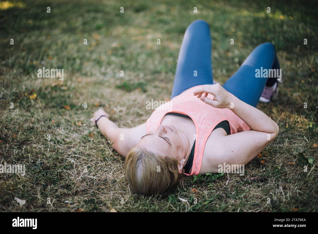Müde Frau, die auf Gras im Park liegt Stockfoto