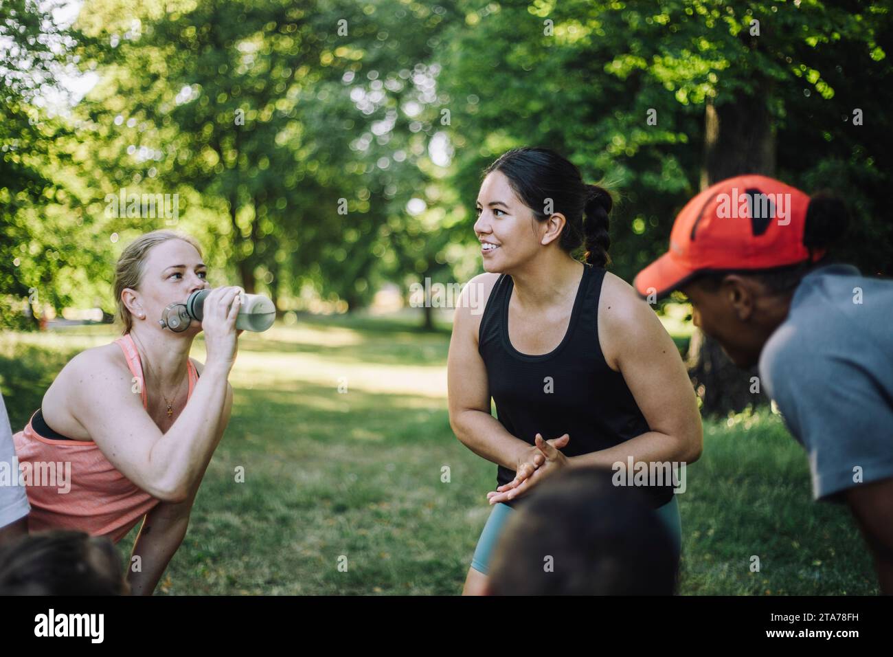 Begeisterte Coach, die während des Trainings im Park mit dem Team diskutiert Stockfoto