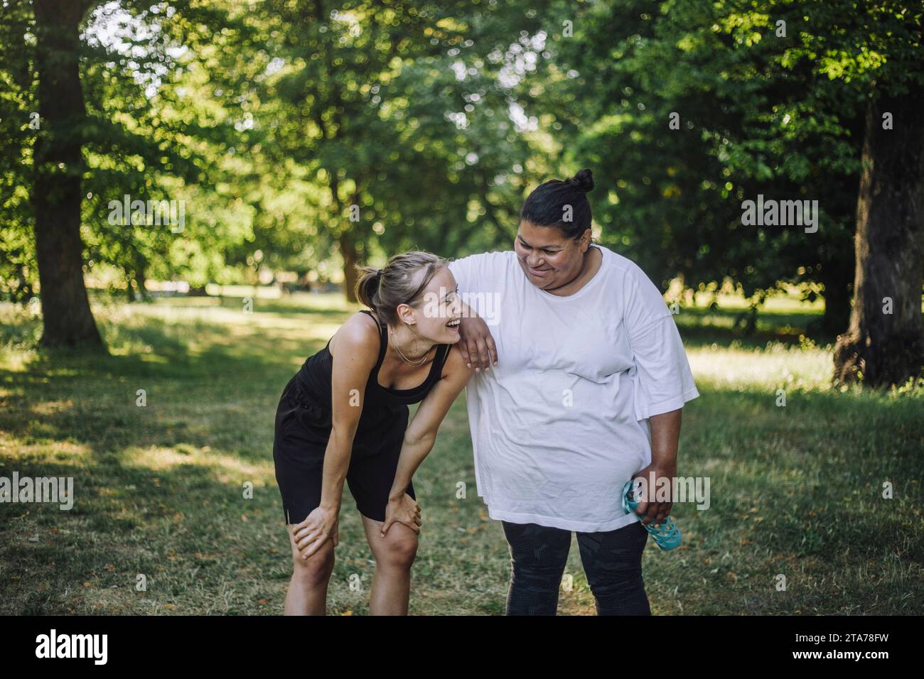 Glückliche, multirassische Freundinnen, die zusammen im Park lachen Stockfoto