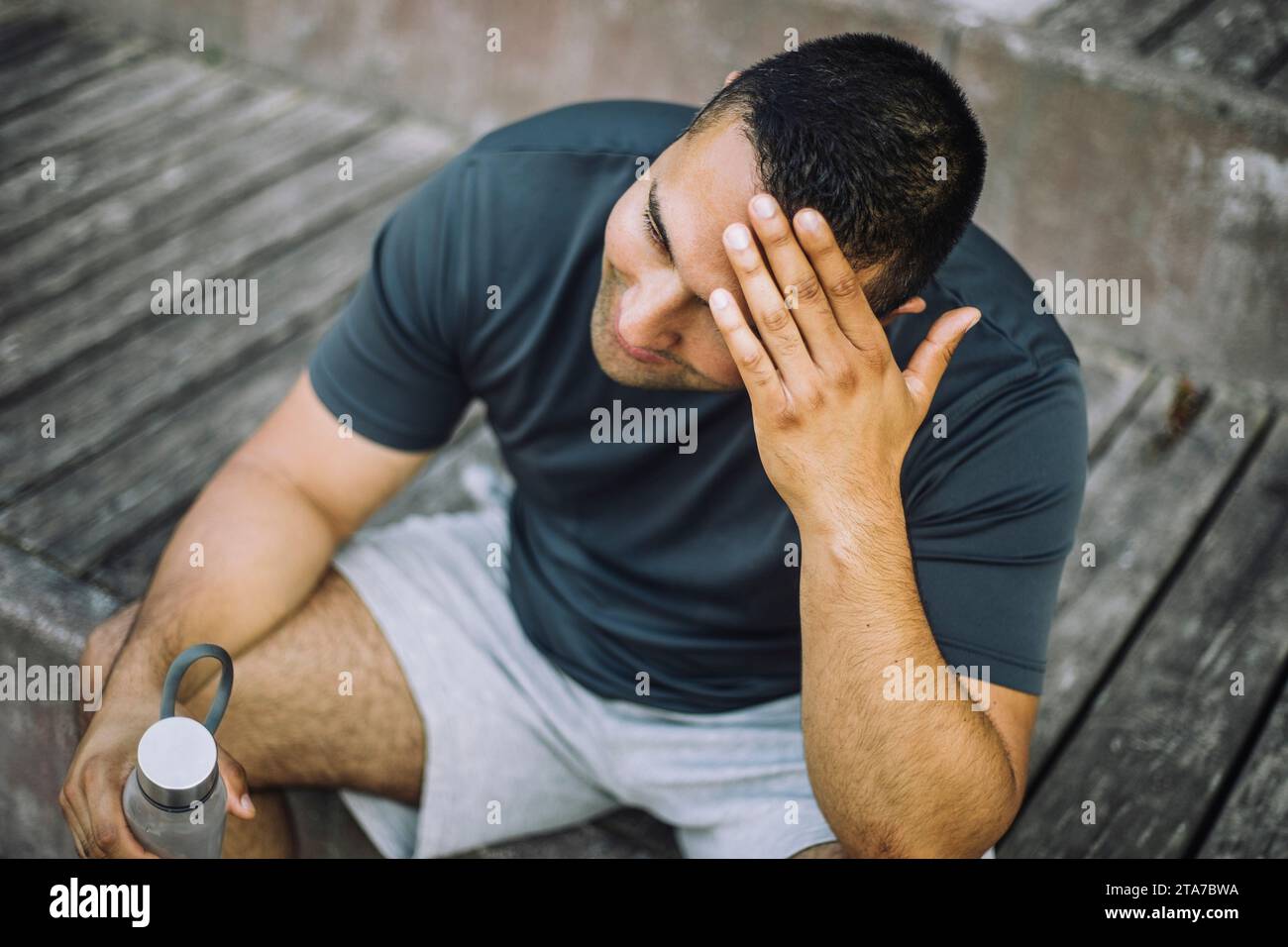 Müder Mann mit Kopf in der Hand, während er auf Stufen sitzt Stockfoto