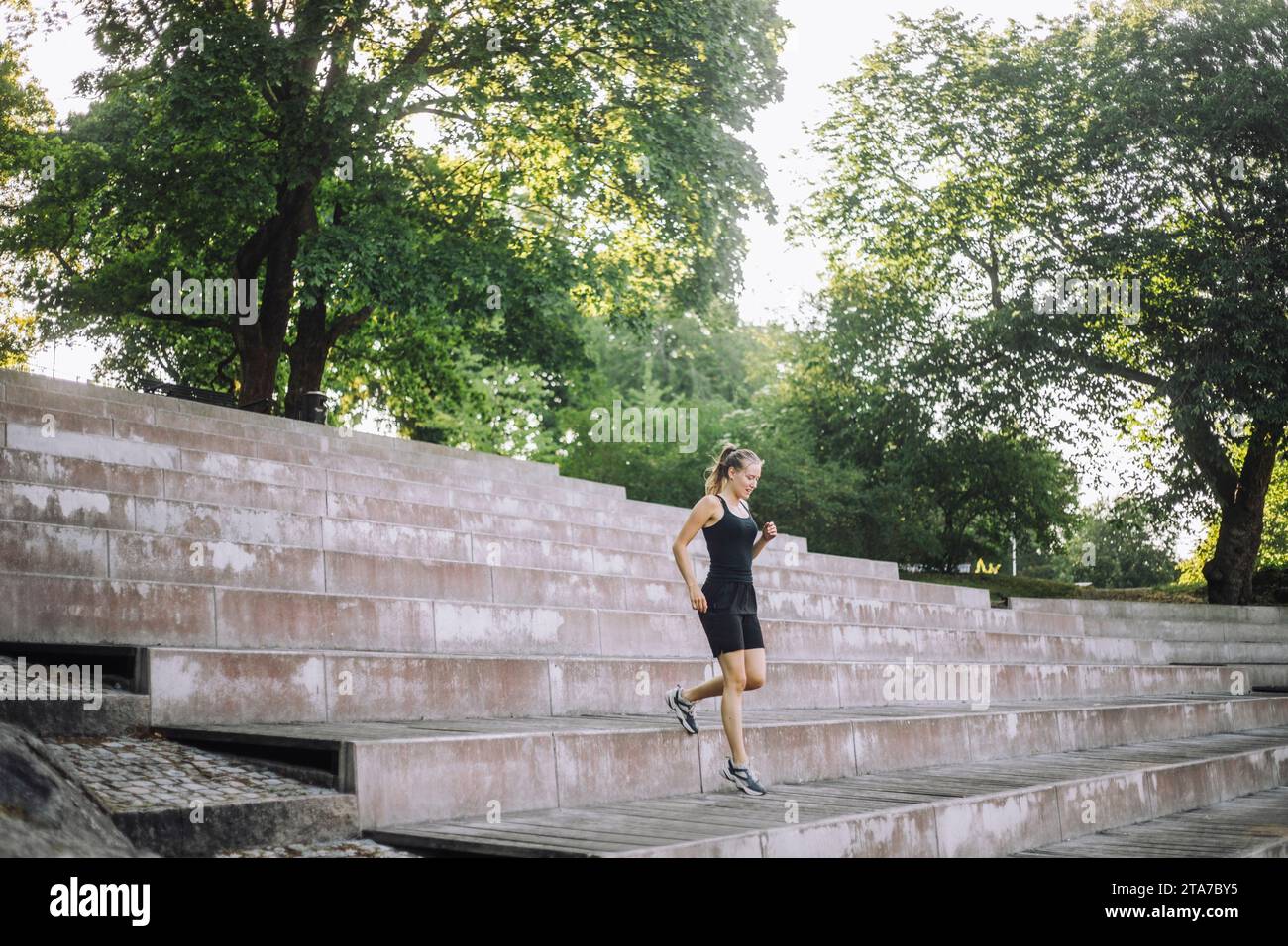 Eine junge Frau, die von den Stufen im Park herunterfährt Stockfoto