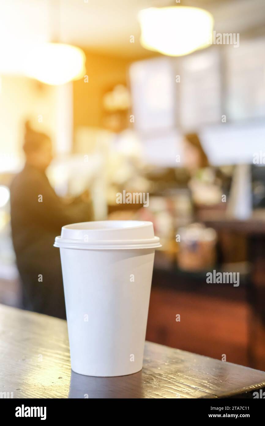 Kaffeetasse zum Mitnehmen mit heißem Getränk auf dem Tisch im Café. Stockfoto