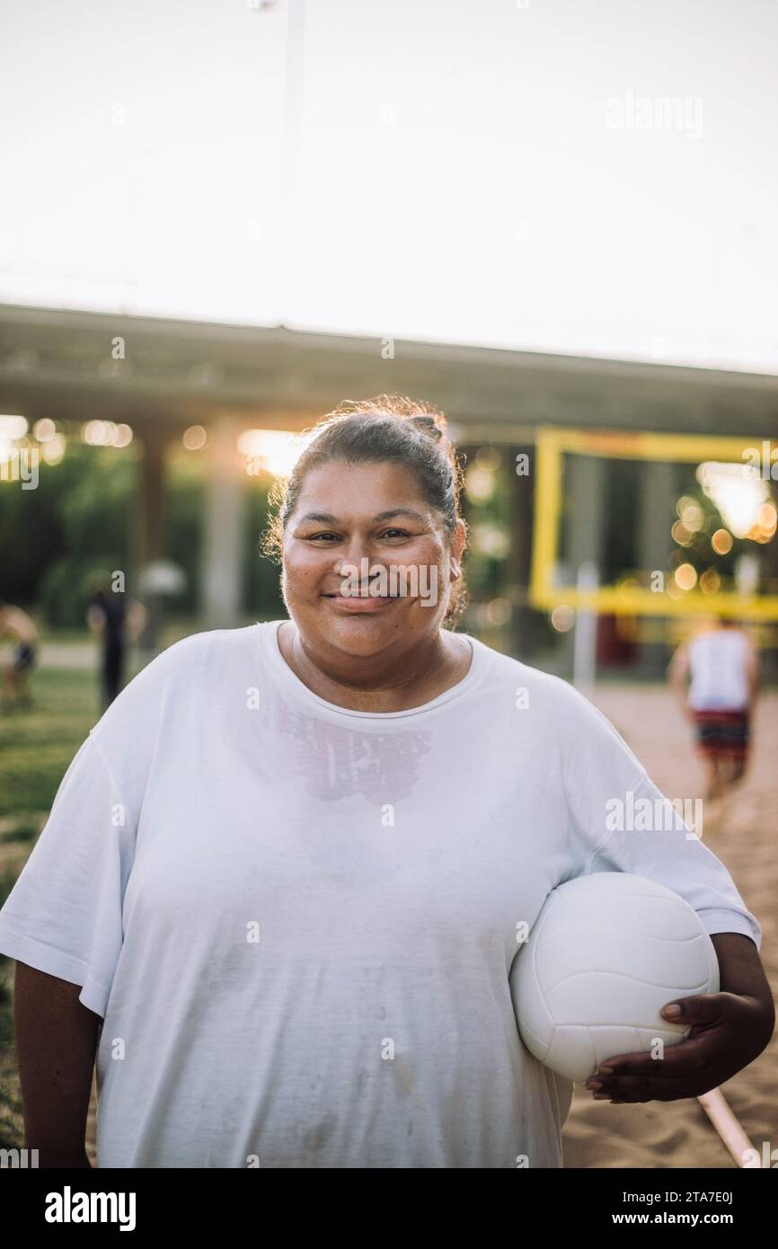 Porträt einer lächelnden übergroßen Frau mit weißem T-Shirt und Volleyball Stockfoto