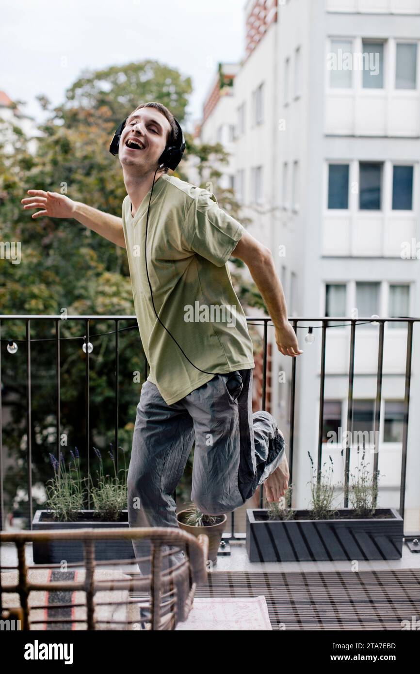 Sorgloser Mann, der Musik hört, während er auf dem Balkon tanzt Stockfoto