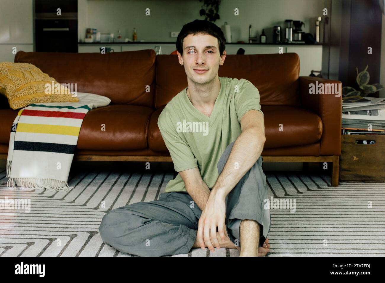 Porträt eines jungen Mannes, der zu Hause auf dem Boden sitzt Stockfoto