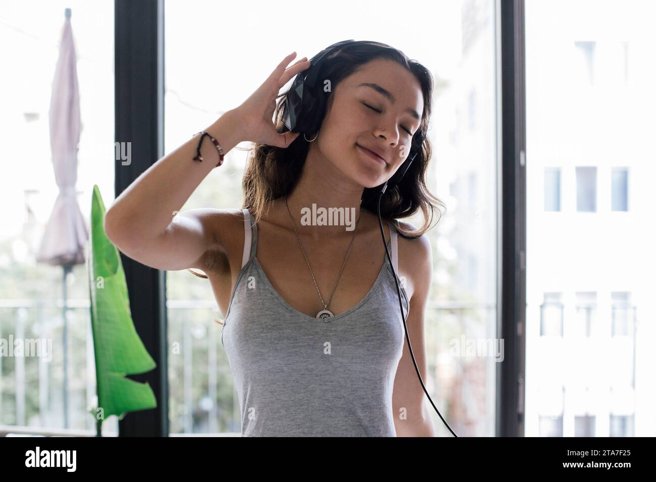 Sorglose junge Frau, die zu Hause Musik über Kopfhörer hört Stockfoto