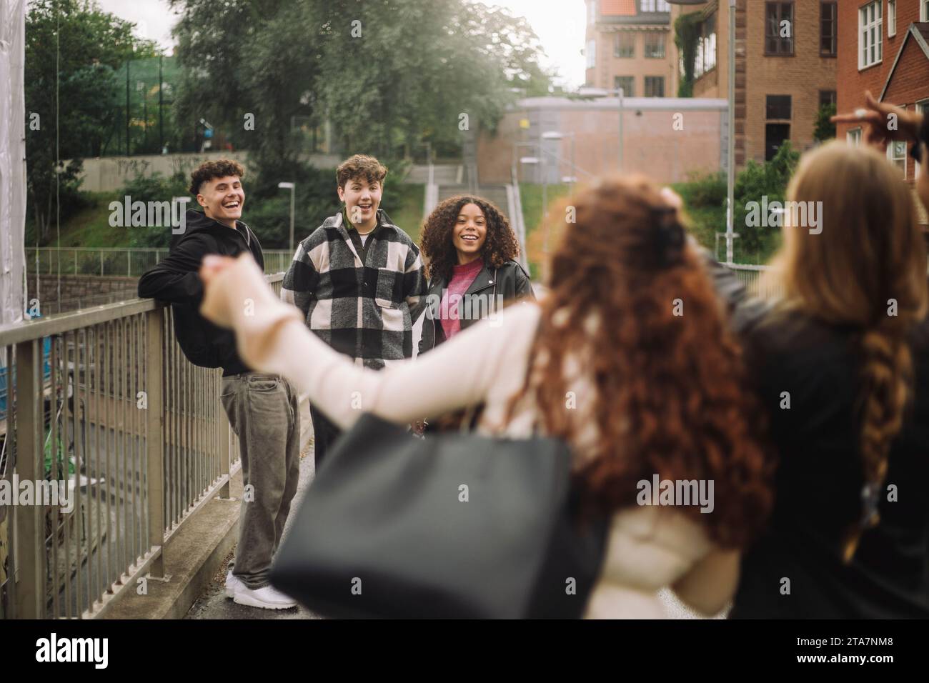 Männliche und weibliche Teenagerfreunde, die Spaß auf dem Fußweg haben Stockfoto