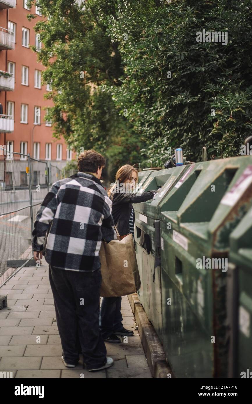 Ein Mädchen, das Müll mit einem männlichen Teenager-Freund auf dem Fußweg wegwirft Stockfoto