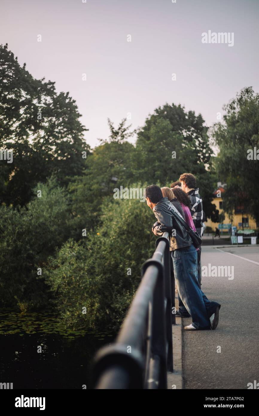 Männliche und weibliche Teenagerfreunde, die sich auf Brückengeländer stützen Stockfoto