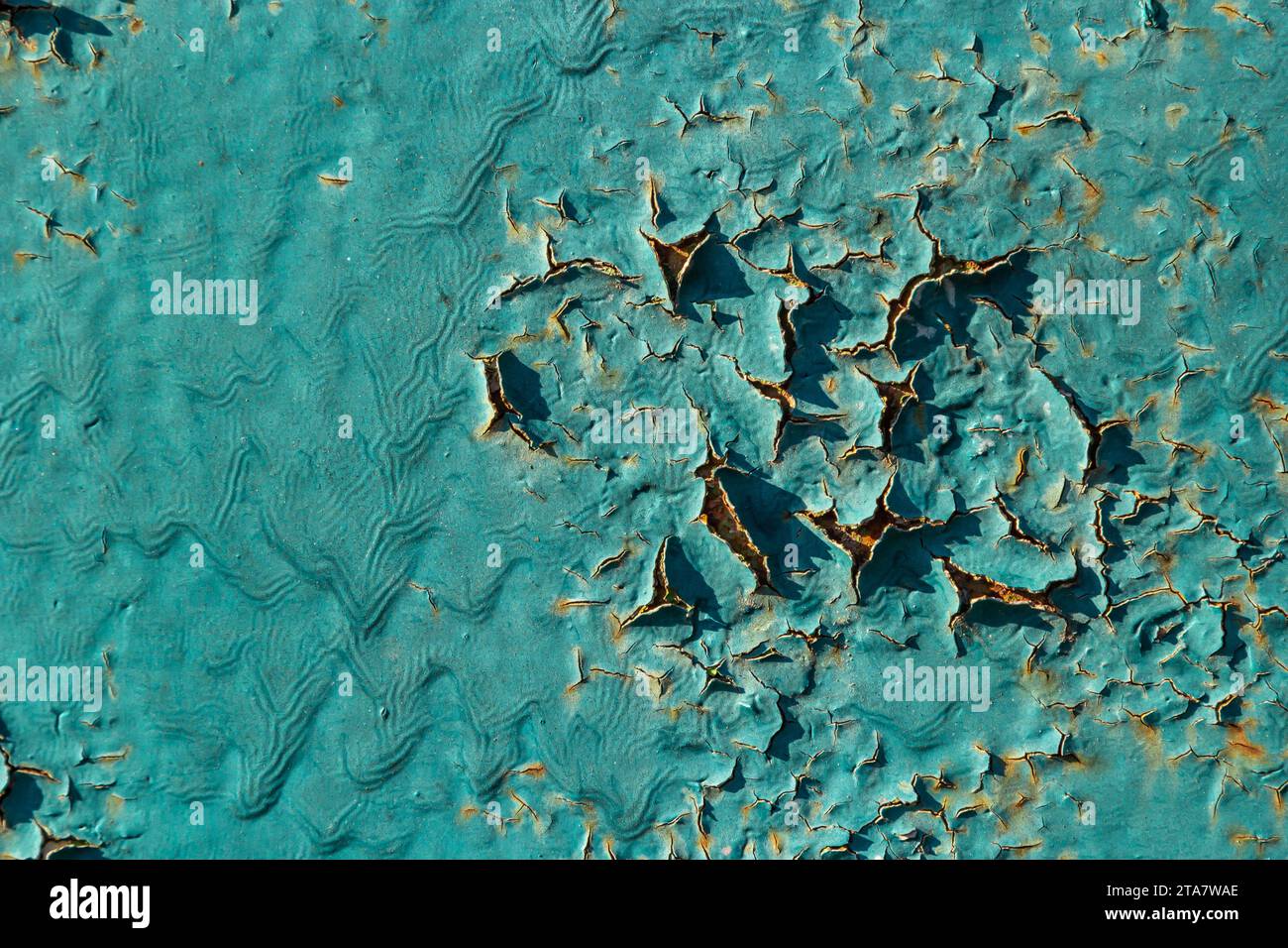 Die Farbe blättert blau an der Wand ab. Alte Betonwand mit rissiger abblätternder Farbe. Verwitterte, rauh lackierte Oberfläche mit Rissen- und Abschälungsmustern. Hig Stockfoto