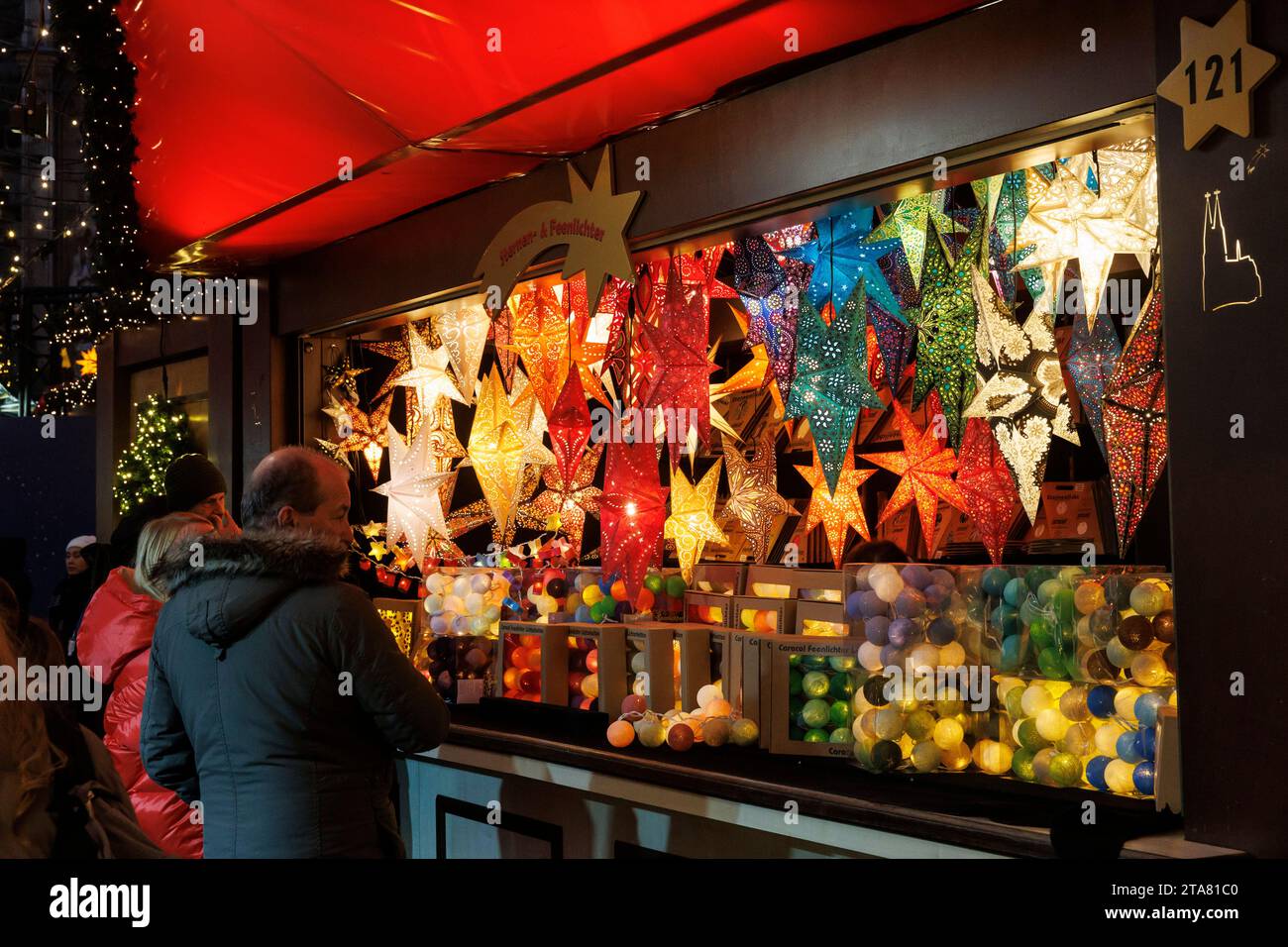 Stehen Sie mit Sternen und Weihnachtsbaumkugeln auf dem Weihnachtsmarkt am Roncalliplatz vor dem Dom, Köln. Stand mit Sternen und Stockfoto