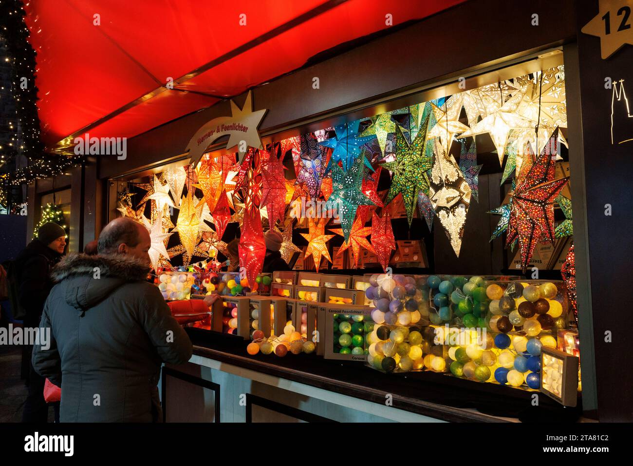 Stehen Sie mit Sternen und Weihnachtsbaumkugeln auf dem Weihnachtsmarkt am Roncalliplatz vor dem Dom, Köln. Stand mit Sternen und Stockfoto