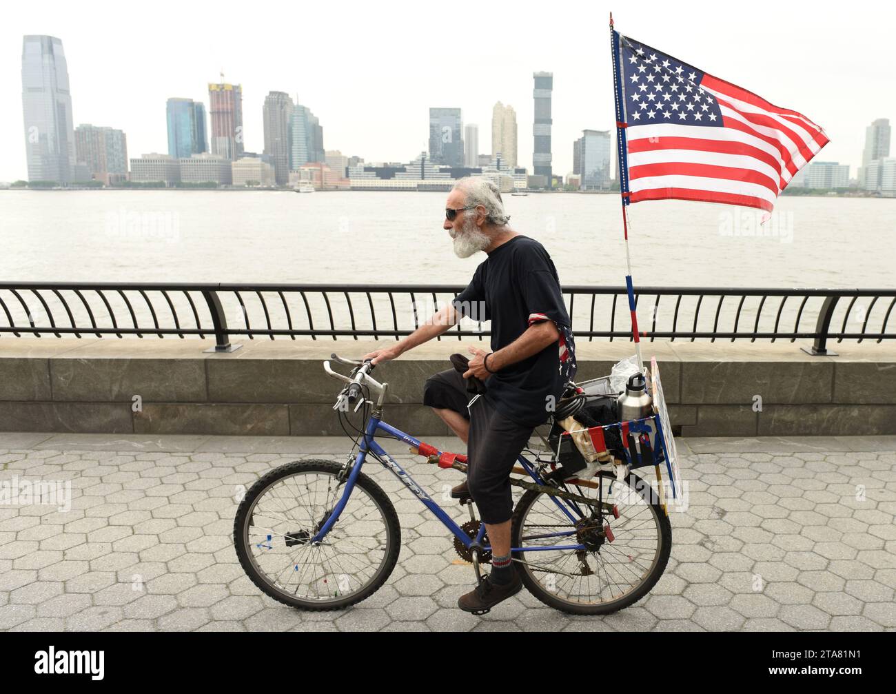 New York, USA - 28. Mai 2018: Ein Mann mit US-Flagge auf einem Fahrrad in der Battery Park City Esplanade in New York. Stockfoto