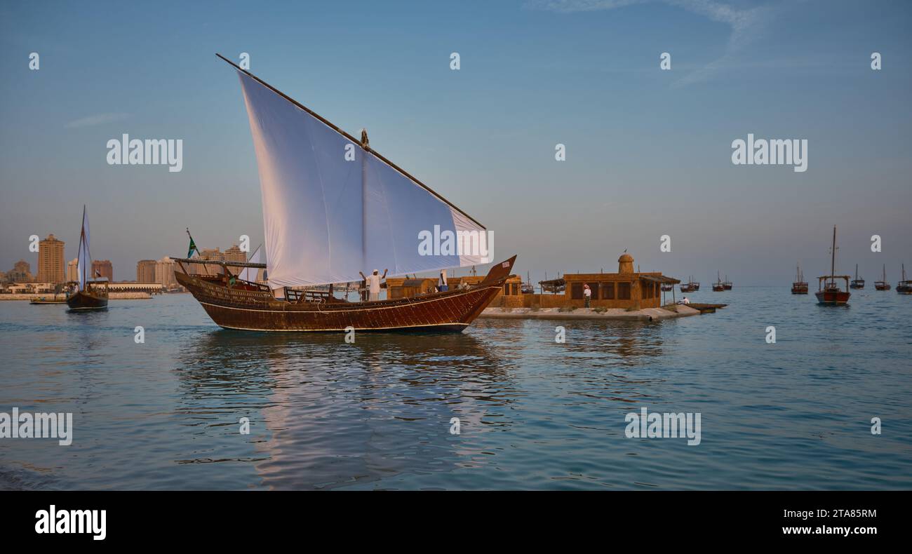 Katara13th traditionelles Dhow-Festival in Doha Katar Sonnenuntergang mit traditionellen Daus im arabischen Golf mit Fahnen der teilnehmenden Länder. Stockfoto