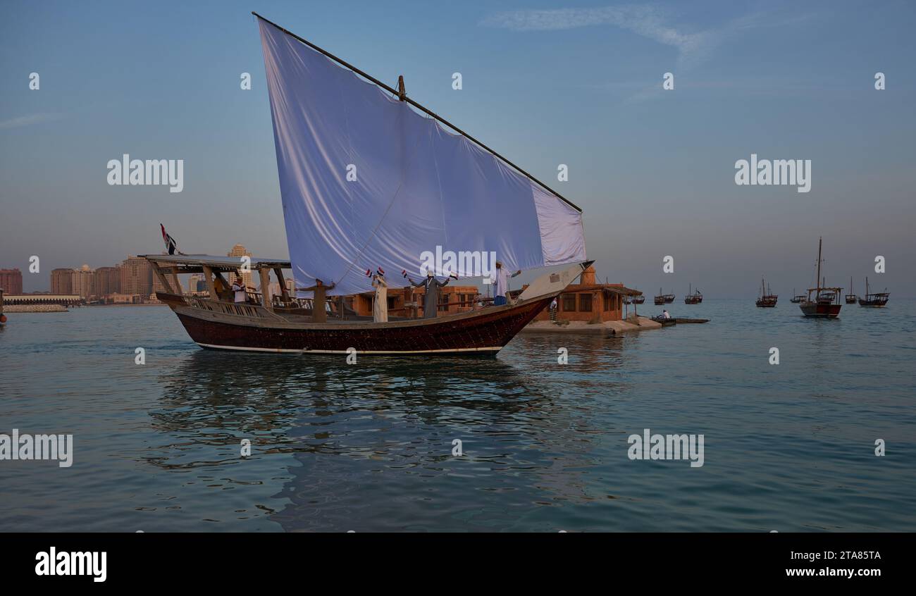 Katara13th traditionelles Dhow-Festival in Doha Katar Sonnenuntergang mit traditionellen Daus im arabischen Golf mit Fahnen der teilnehmenden Länder. Stockfoto