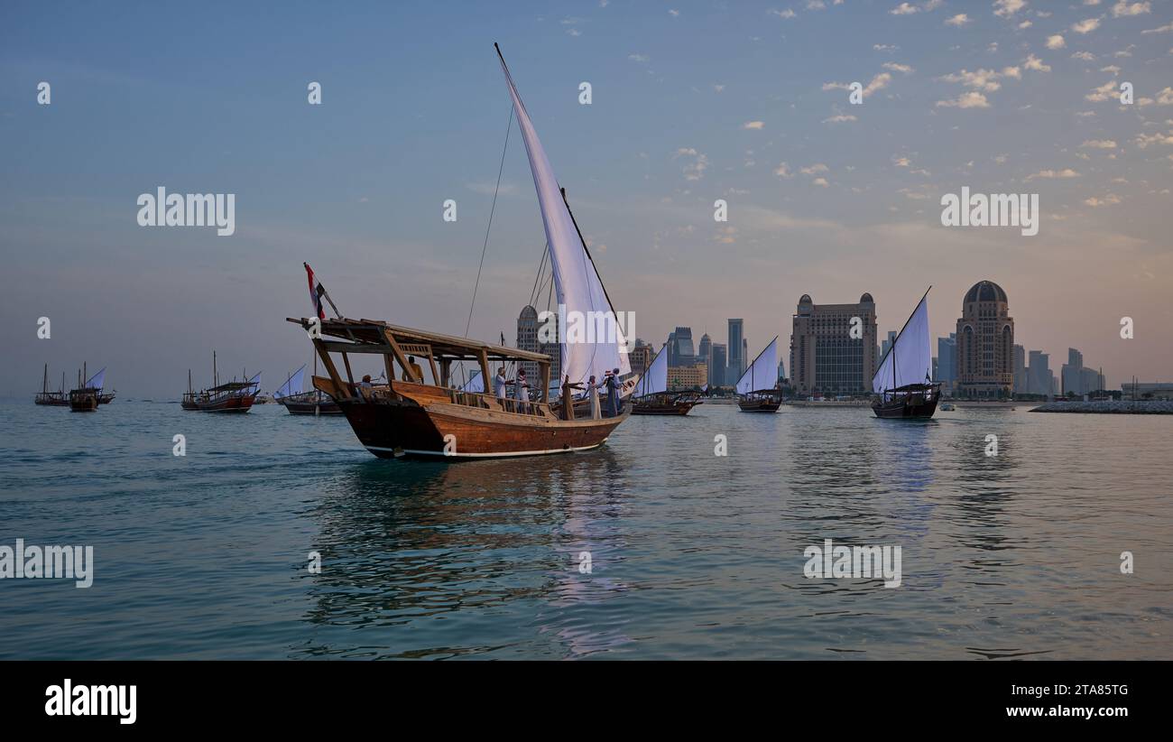 Katara13th traditionelles Dhow-Festival in Doha Katar Sonnenuntergang mit traditionellen Daus im arabischen Golf mit Fahnen der teilnehmenden Länder. Stockfoto