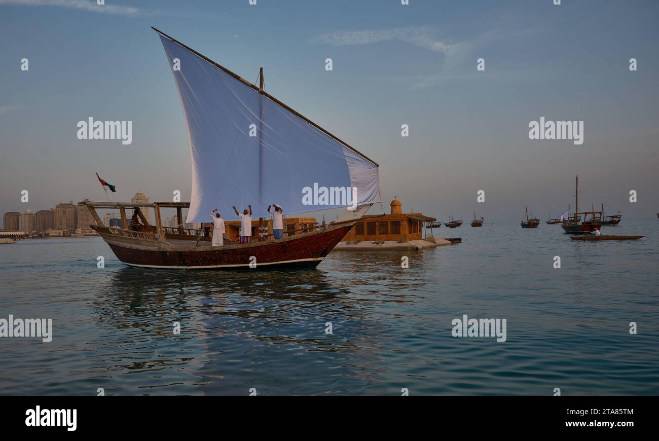 Katara13th traditionelles Dhow-Festival in Doha Katar Sonnenuntergang mit traditionellen Daus im arabischen Golf mit Fahnen der teilnehmenden Länder. Stockfoto