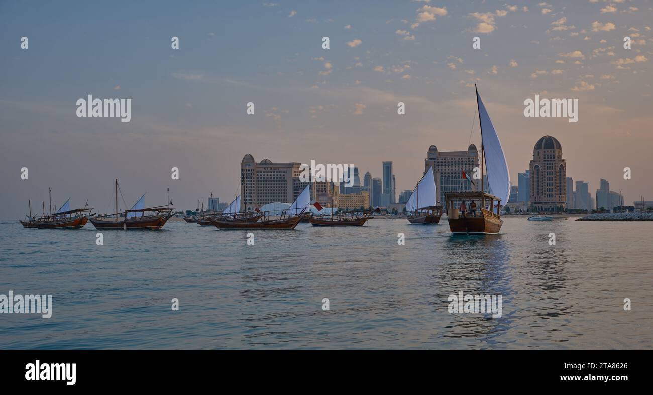 Katara13th traditionelles Dhow-Festival in Doha Katar Sonnenuntergang mit traditionellen Daus im arabischen Golf mit Fahnen der teilnehmenden Länder. Stockfoto