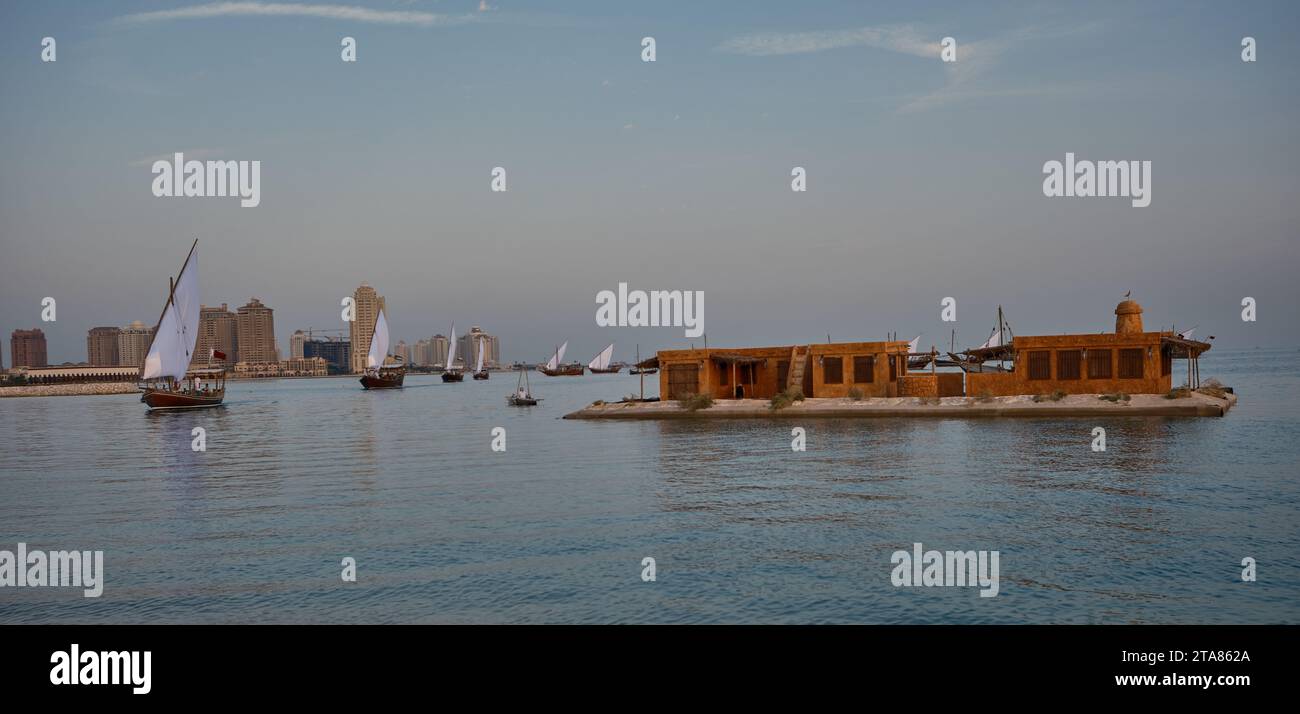 Katara13th traditionelles Dhow-Festival in Doha Katar Sonnenuntergang mit traditionellen Daus im arabischen Golf mit Fahnen der teilnehmenden Länder. Stockfoto