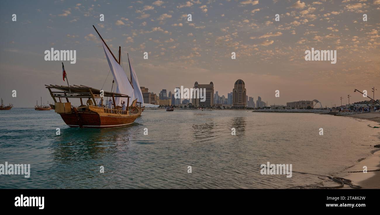 Katara13th traditionelles Dhow-Festival in Doha Katar Sonnenuntergang mit traditionellen Daus im arabischen Golf mit Fahnen der teilnehmenden Länder. Stockfoto