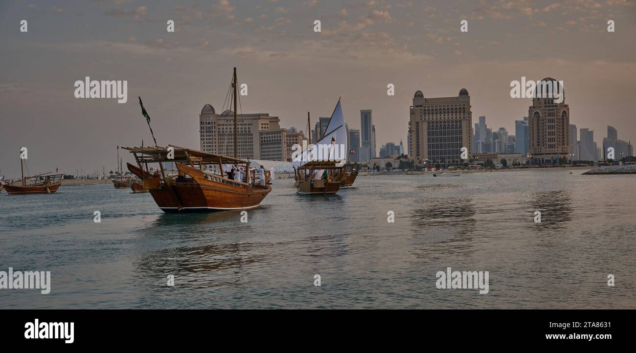 Katara13th traditionelles Dhow-Festival in Doha Katar Sonnenuntergang mit traditionellen Daus im arabischen Golf mit Fahnen der teilnehmenden Länder. Stockfoto