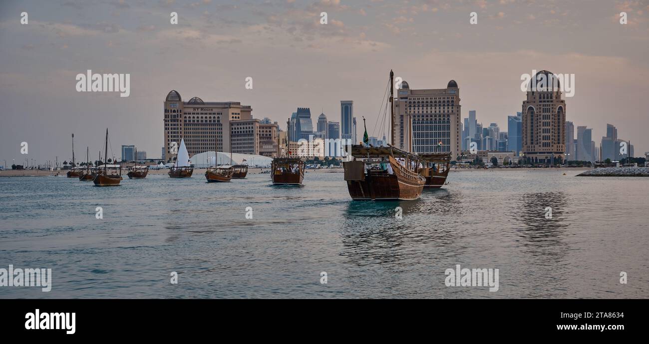 Katara13th traditionelles Dhow-Festival in Doha Katar Sonnenuntergang mit traditionellen Daus im arabischen Golf mit Fahnen der teilnehmenden Länder. Stockfoto