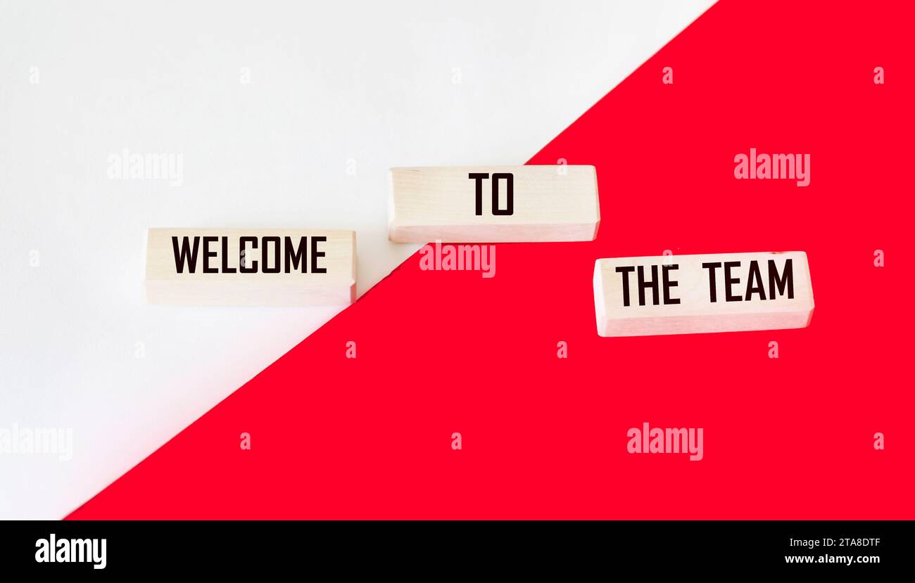 Willkommen bei unserem Teamsymbol. Concept Words Willkommen bei unserem Team auf Holzblöcken. Schöner rot-weißer Hintergrund. Stockfoto