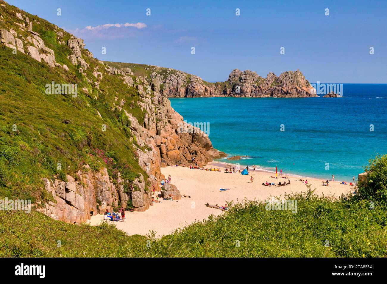 20. Mai 2023: Porthcurno, Cornwall, Großbritannien - Porthcurno Cove und Logan Rock an einem schönen sonnigen Frühlingstag, an dem die Menschen den Strand und das Meer unter B genießen Stockfoto