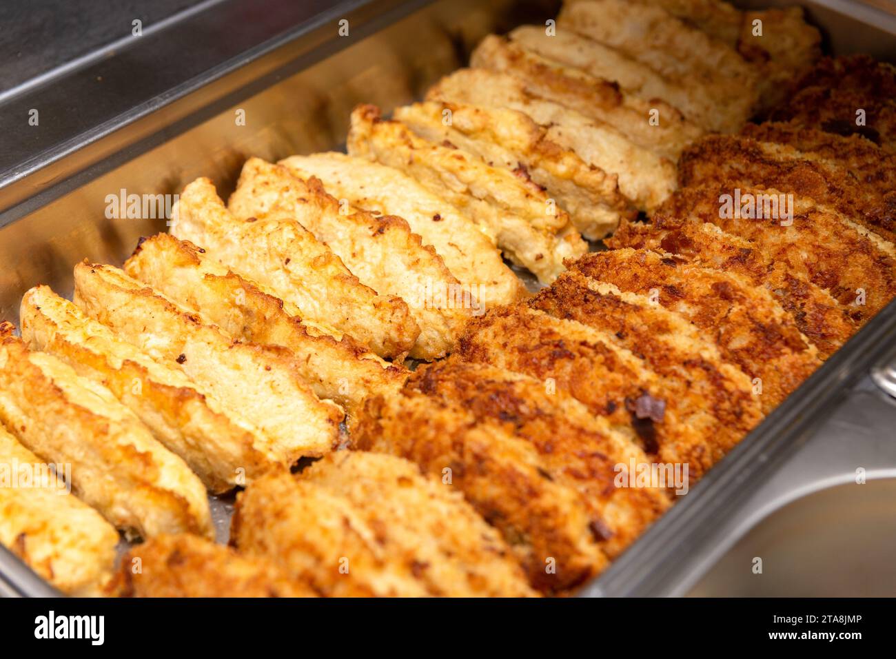 Reihen Schnitzel in einem Metalltablett in einer Restaurantküche Stockfoto