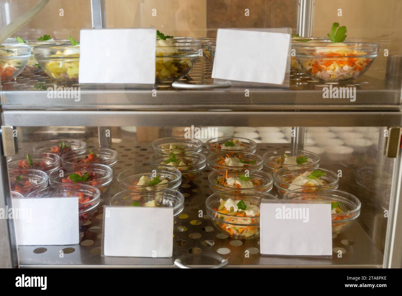 Teller mit verschiedenen Backwaren im Fenster der Cafeteria. Kühlende Salate im Speisesaal oder in der Cafeteria Stockfoto