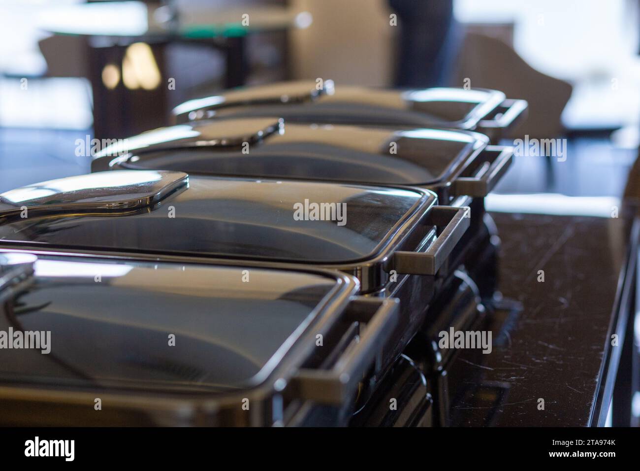 Reihe geschlossener Buffetgerichte im Partybanketsaal. Wartungsbereite Scheuerschale aus Edelstahl am Buffet. Stockfoto