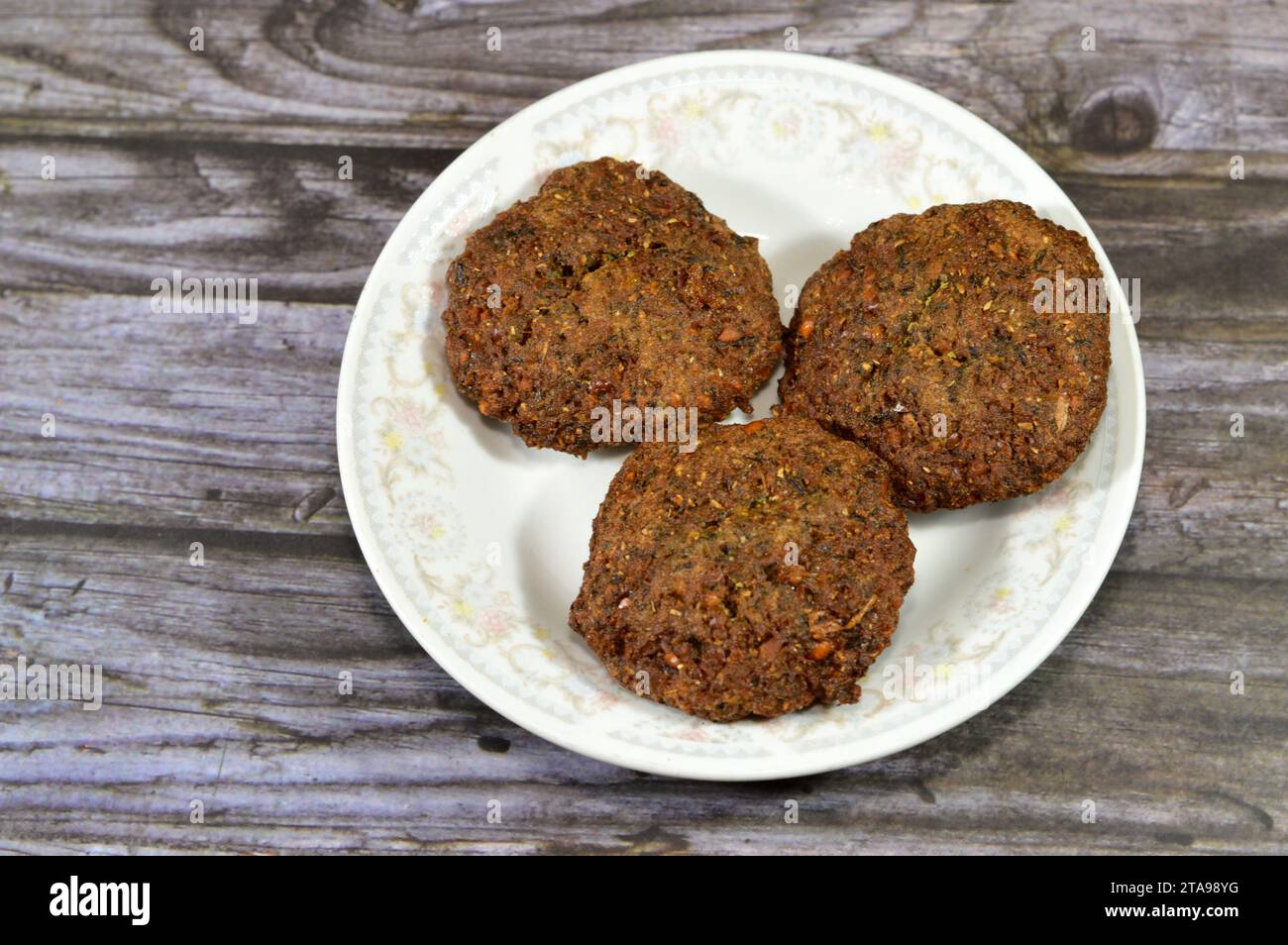 Traditionelle ägyptische frittierte Falafelbällchen, grüner Burger, hergestellt aus gemahlenen Kichererbsen und breiten Bohnen, frittierte Bällchen oder Patty-Fritter, mit Sesam Stockfoto