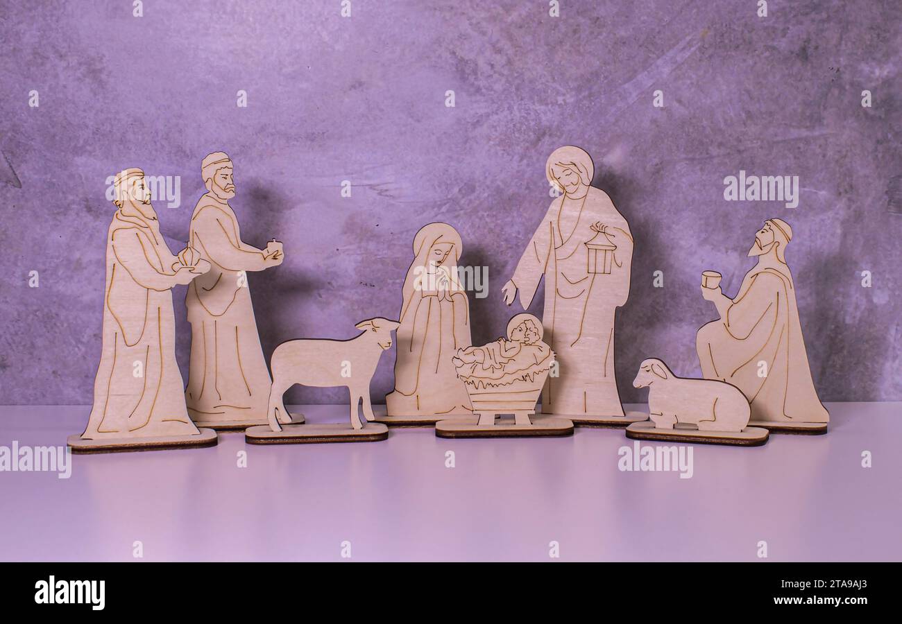 Ein hölzernes Weihnachtskrippe-Set mit der heiligen Familie, die das Jesuskind mit Bokeh-Hintergrund ansieht. Stockfoto