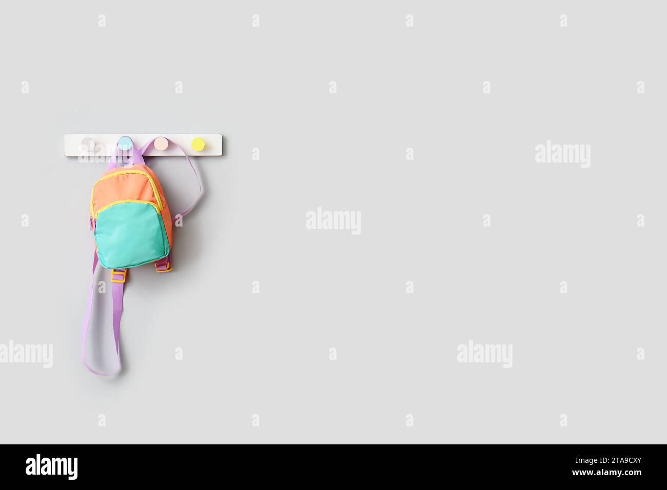 Stylischer Schulrucksack, der an einer hellen Wand hängt Stockfoto