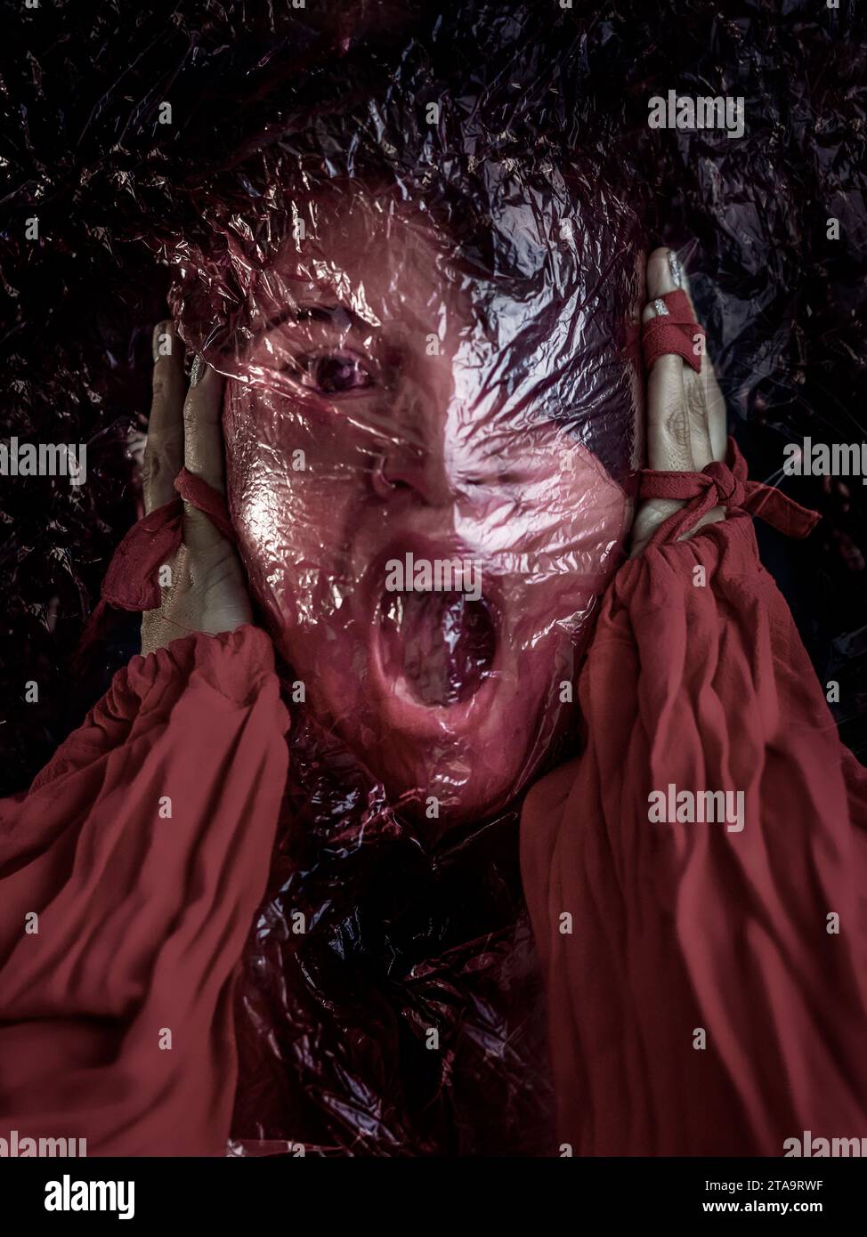 Frau mit einem roten durchsichtigen Beutel im Gesicht, die Hände drücken sich gegen die Ohren, der Mund ist offen und zeigt sich in Not und Verzweiflung. Illustrati Stockfoto