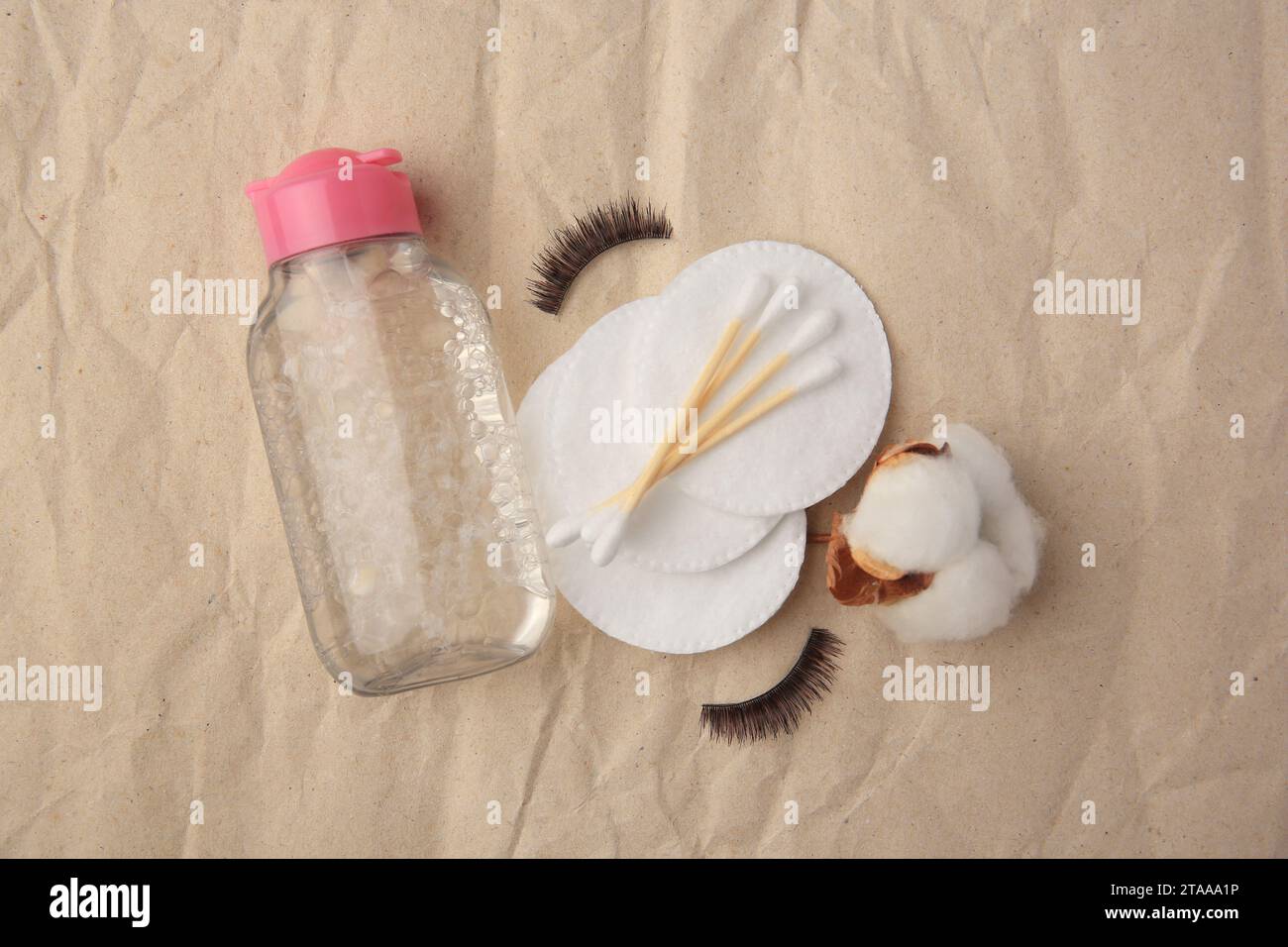 Flache Lagenkomposition mit Make-up-Entferner und falschen Wimpern auf zerknittertem Papier Stockfoto