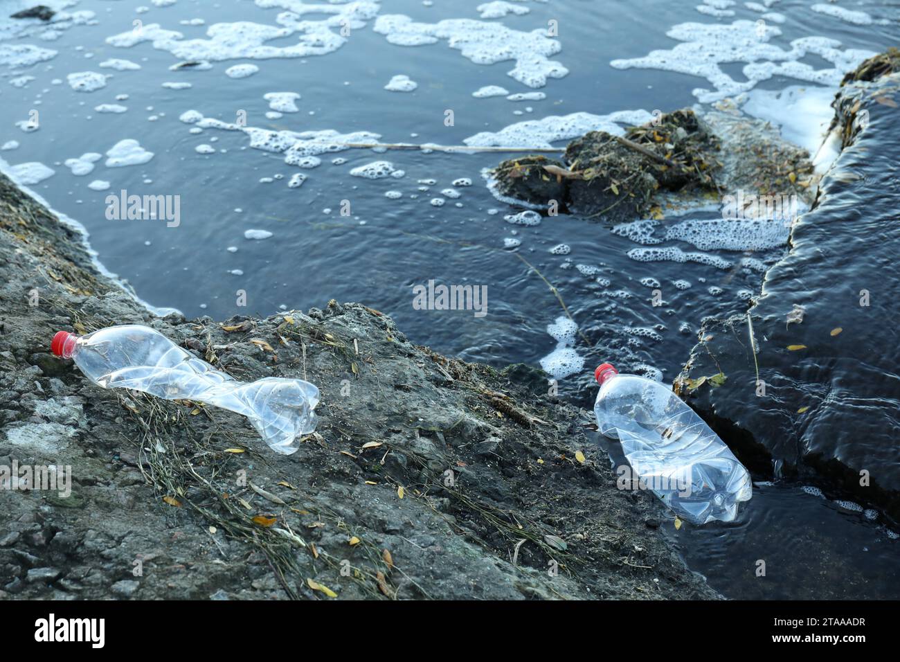 Gebrauchte Kunststoffflaschen in der Nähe von Wasser im Freien. Umweltverschmutzung Stockfoto