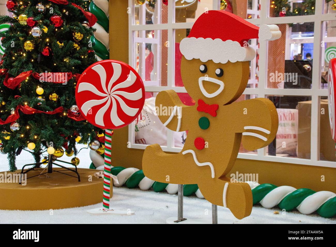 Ein süßer Lebkuchenmann, ein Süßwarenmann mit der dekorierten Kiefer und die bunten Süßigkeiten mit der weihnachtlichen Atmosphäre im Suria KLCC, Kuala Lumpur, Malaysia Stockfoto