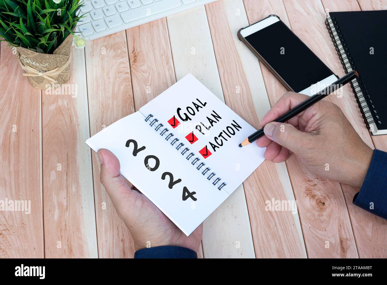 2024 Ziel, Plan, Aktionstext auf Notizblock mit Bürozubehör. Stockfoto