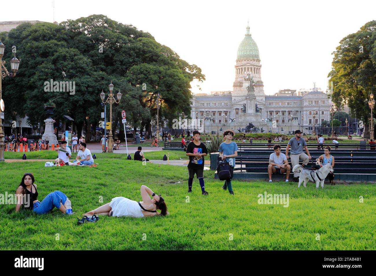 Die Leute entspannen sich in der Abenddämmerung auf der Plaza Mariano Moreno mit der Plaza del Congreso und dem Gebäude des Palastes des argentinischen Nationalkongresses im Hintergrund.Buenos Aires.Argentinien Stockfoto