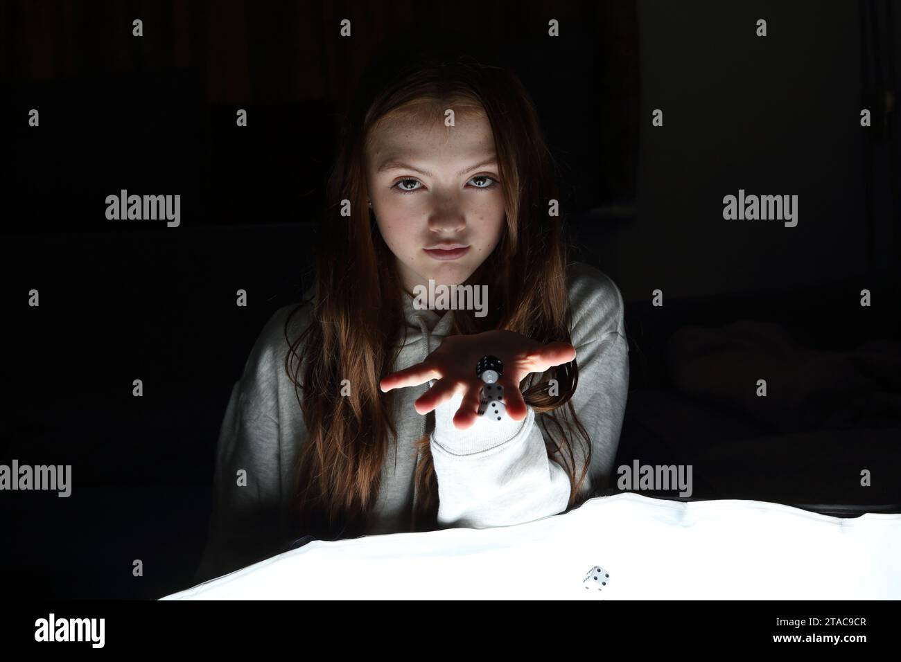 Teenager-Mädchen würfelt und wirft Würfel aus ihren Händen Stockfoto