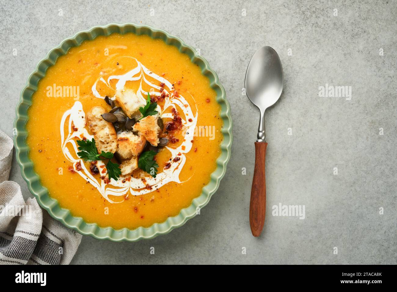 Kürbis-Karotten-Creme-Suppe mit Kräutern, Gewürzen und Samen in der Schüssel auf grauem Betontischhintergrund im rustikalen Stil. Thanksgiving traditionelles Autom Stockfoto