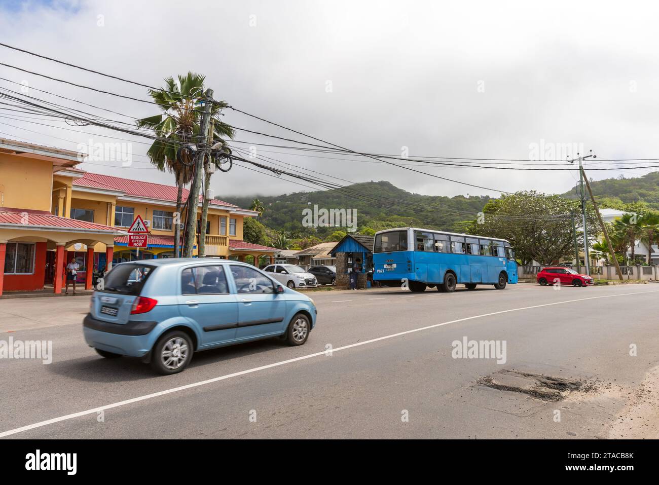 Anse Royale, Seychellen - 18. August 2023: Straßenblick mit Autos und Bus, Einheimische gehen die Straße Stockfoto